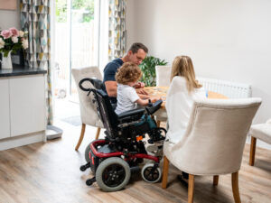 Family sitting together at home, including a child in a wheelchair, spending quality time around the table.